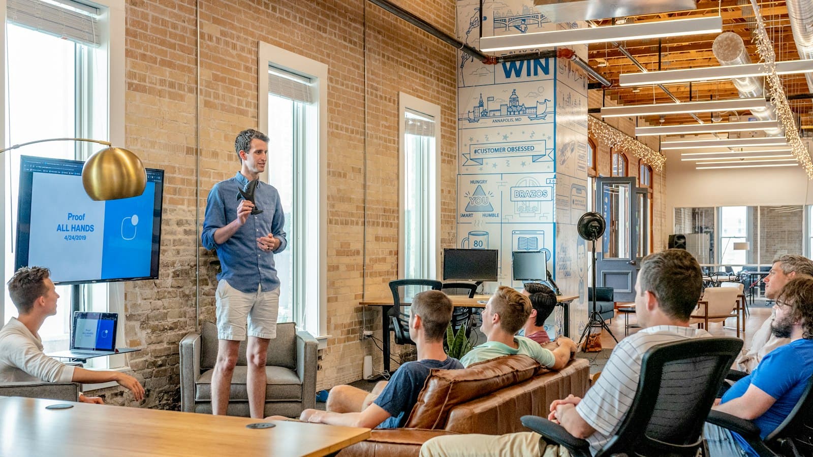 Speaker presenting to a team in a brick-walled office
