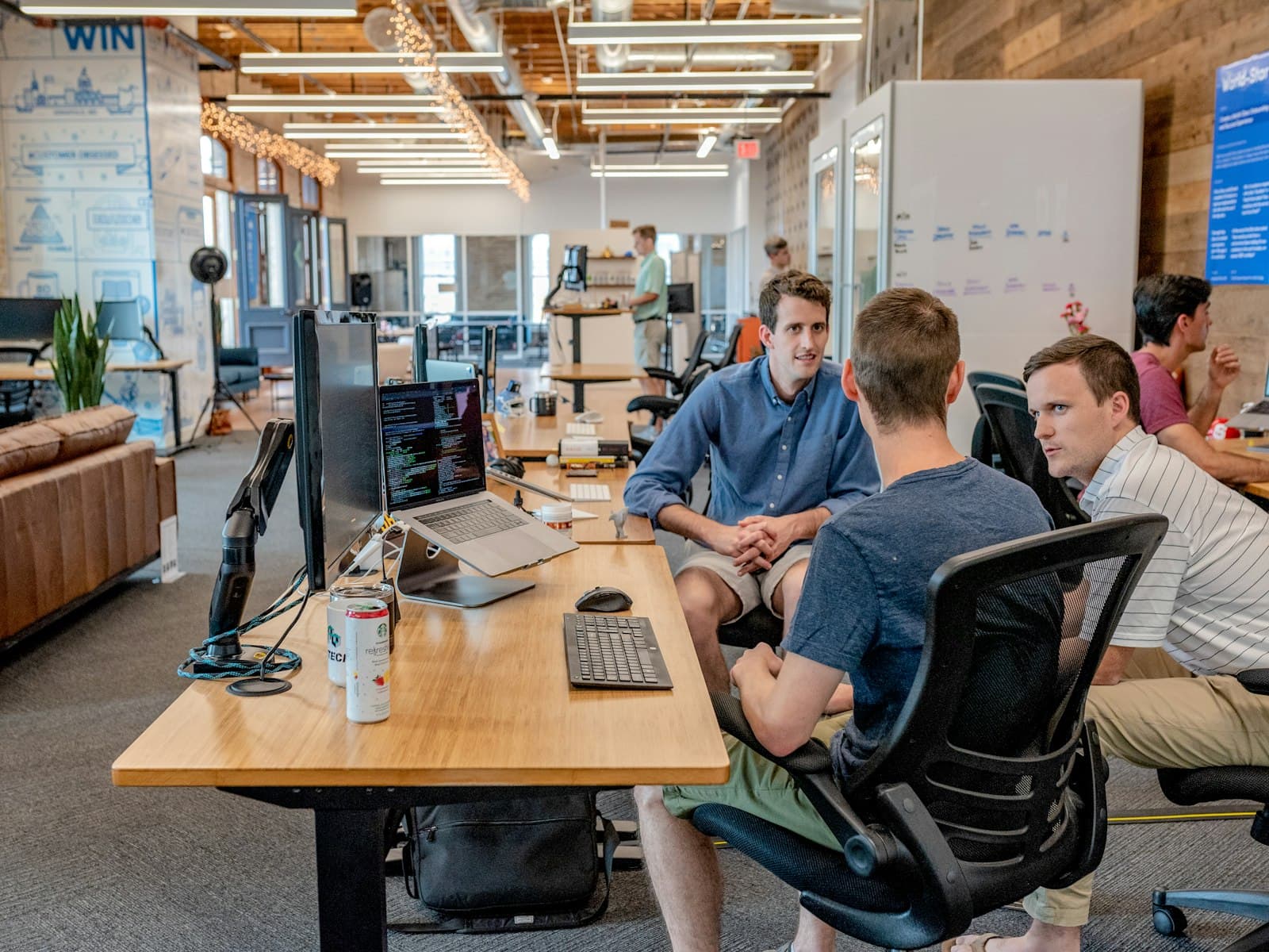 Three colleagues discussing work at an open-plan desk