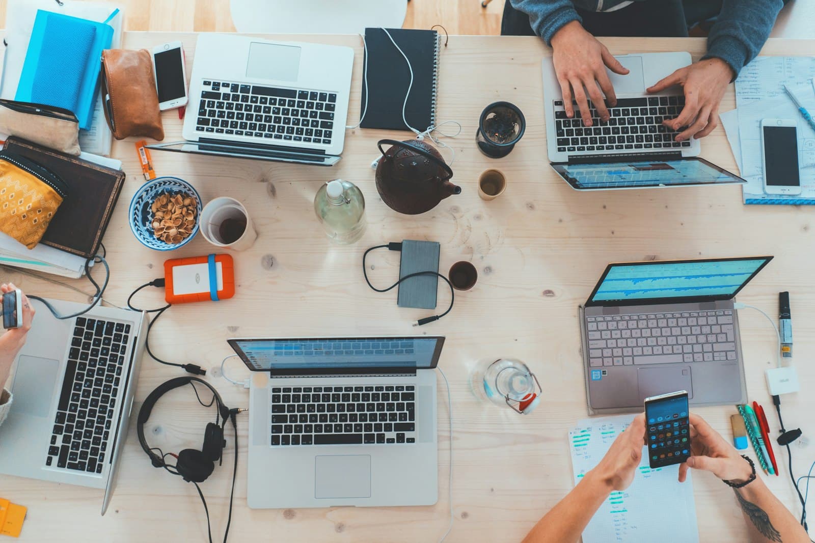 Overhead view of a team working on laptops at a wooden table
